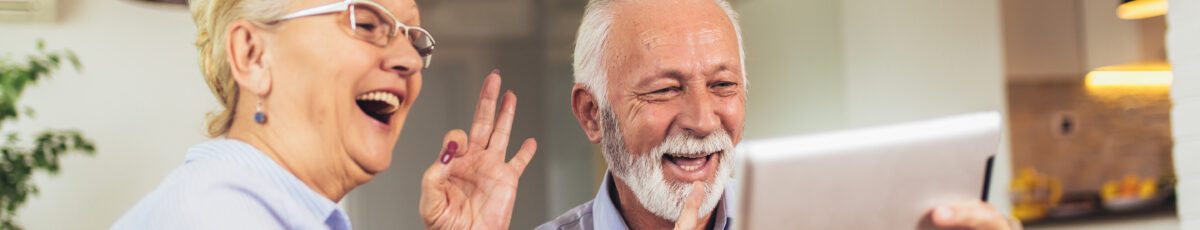 Smiling deaf senior couple talking using sign language on the digital tablet's cam