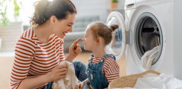 young woman and child doing laundry together and laughing