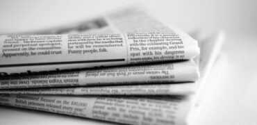 A close up of newspapers piled up on a plain white background.