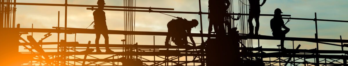 Silhouette of construction team working safely on scaffolding over blurred background of a sunset