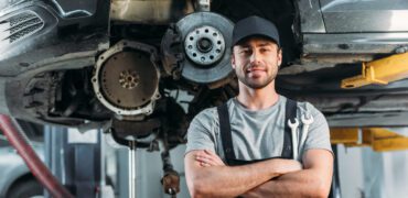 smiling mechanic posing with crossed arms in auto shop