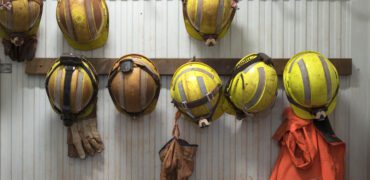 Safety helmets and gloves hang from a rack on a safety site