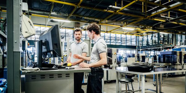Two employees working at a computer together in a warehouse.