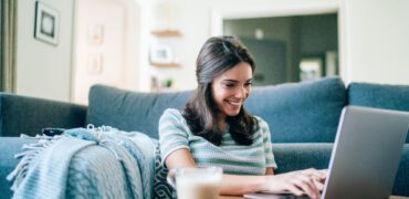 Young woman smiling and using her laptop at home