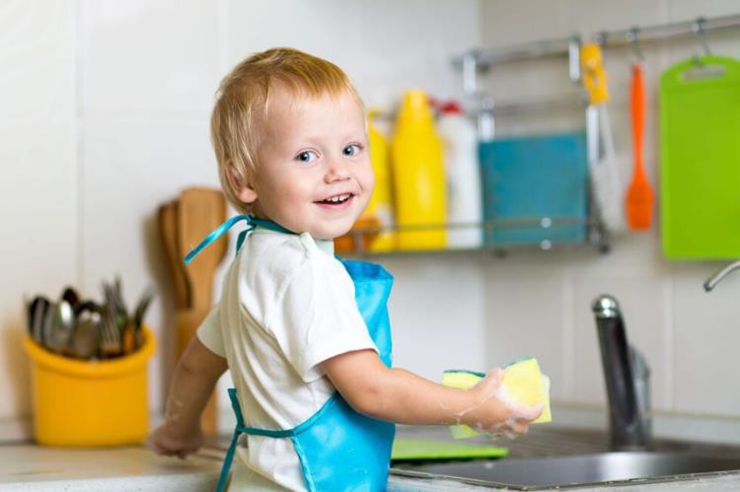 child smiling as he washes the dishes