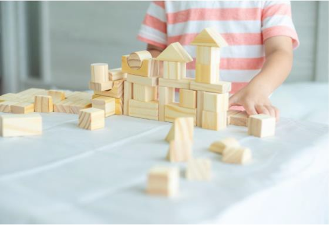 boy building a house with toy blocks