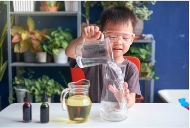 boy pouring a cup of water into a pitcher