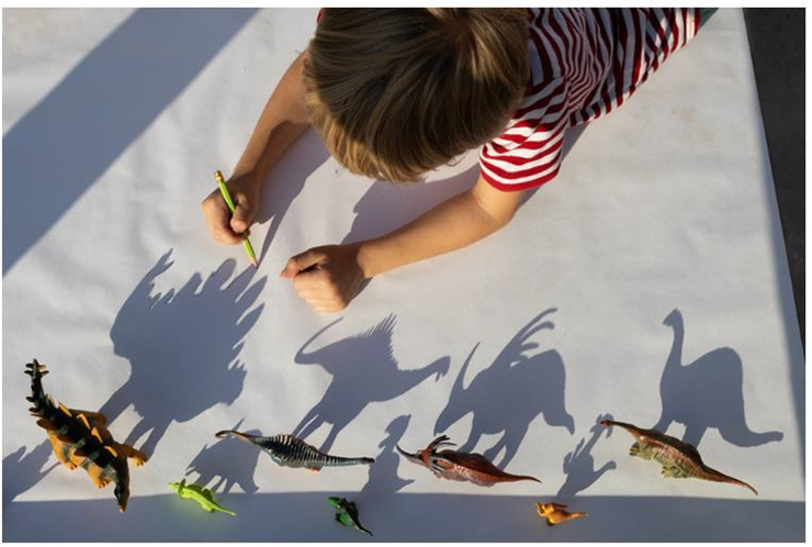 child drawing around shadows of toys