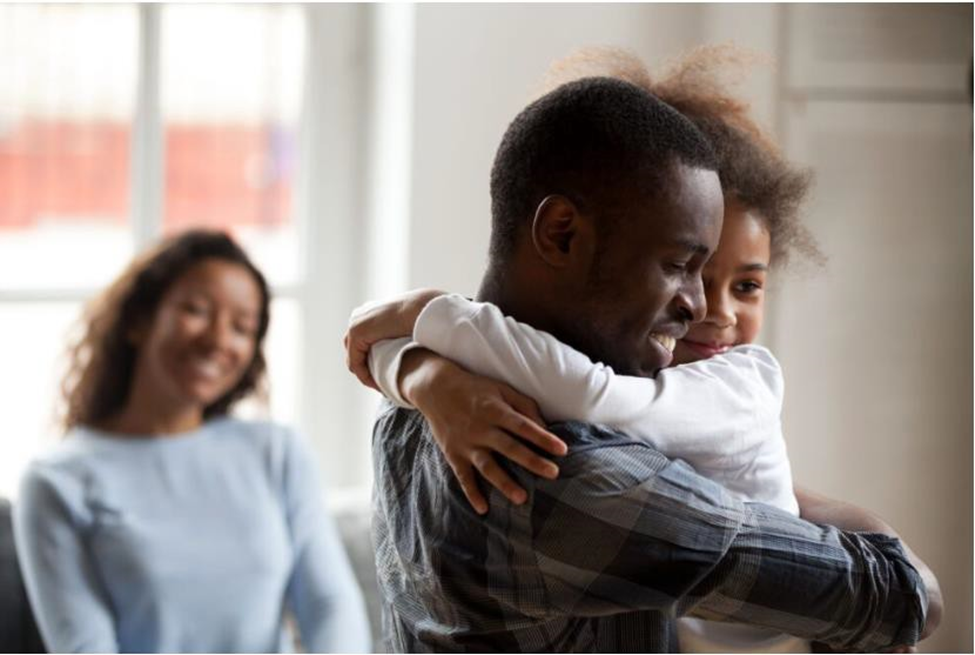 dad hugs daughter while mom looks and smiles