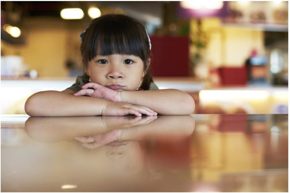 girl with her arms on a table staring at the camera