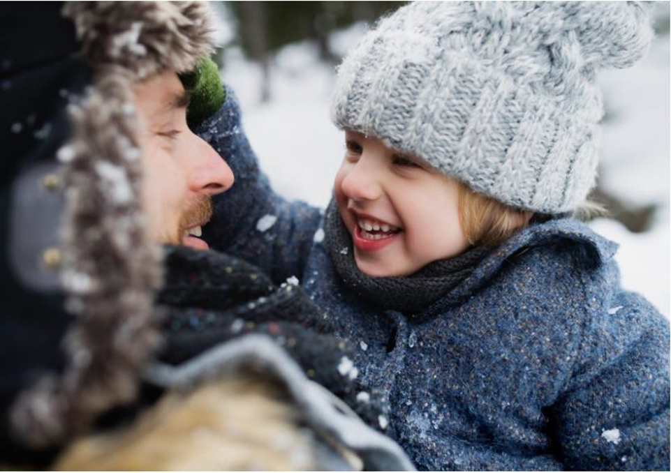 dad and daughter smiling at each other in the snow