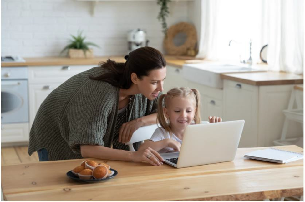 girl using a laptop while mom looks behind her