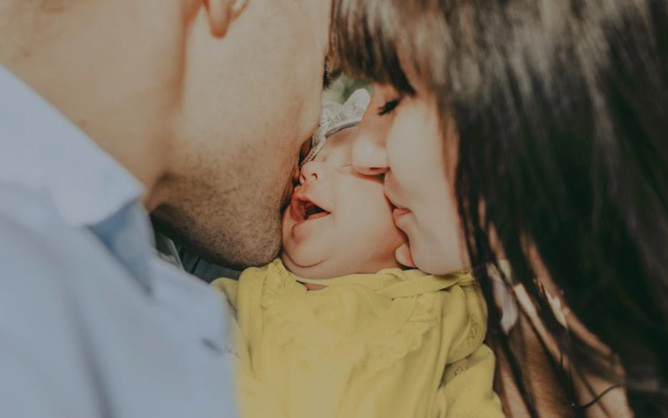 mom and dad both kissing baby