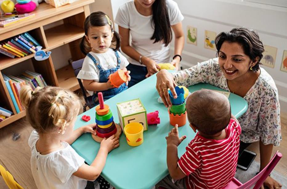 kids playing in a table with the child care provider