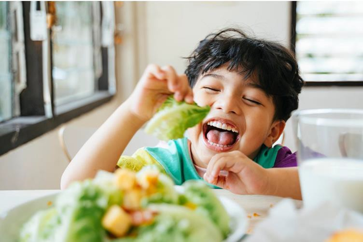 Boy happily eating salad