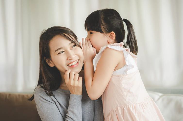 girl whispering in her mom's ear
